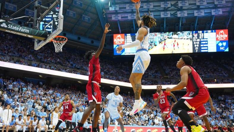 Jan 21, 2023; Chapel Hill, North Carolina, USA; North Carolina Tar Heels guard R.J. Davis (4) shoots as North Carolina State Wolfpack forward Ebenezer Dowuona (21) and guard LJ Thomas (4) defend in the second half at Dean E. Smith Center. Mandatory Credit: Bob Donnan-USA TODAY Sports