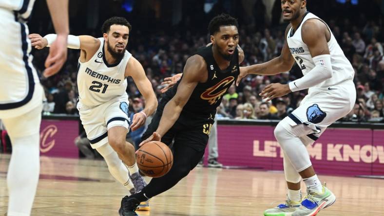 Feb 2, 2023; Cleveland, Ohio, USA; Cleveland Cavaliers guard Donovan Mitchell (45) drives to the basket between Memphis Grizzlies guard Tyus Jones (21) and forward Xavier Tillman (2) during the first half at Rocket Mortgage FieldHouse. Mandatory Credit: Ken Blaze-USA TODAY Sports