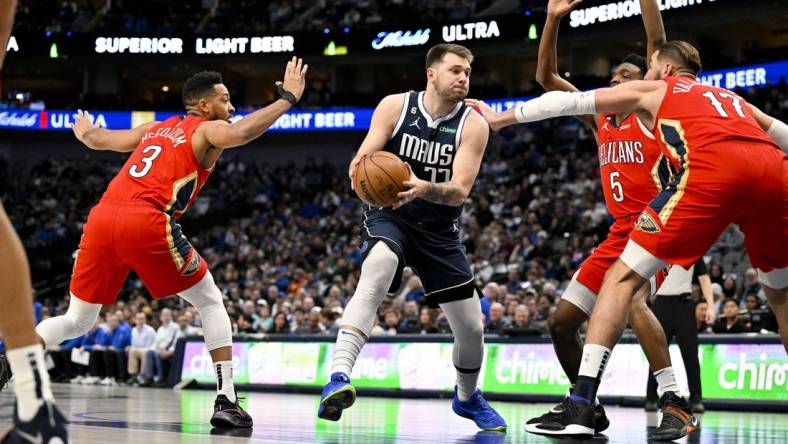 Feb 2, 2023; Dallas, Texas, USA; Dallas Mavericks guard Luka Doncic (77) drives to the basket past New Orleans Pelicans guard CJ McCollum (3) and forward Herbert Jones (5) and center Jonas Valanciunas (17) during the first quarter at the American Airlines Center. Mandatory Credit: Jerome Miron-USA TODAY Sports