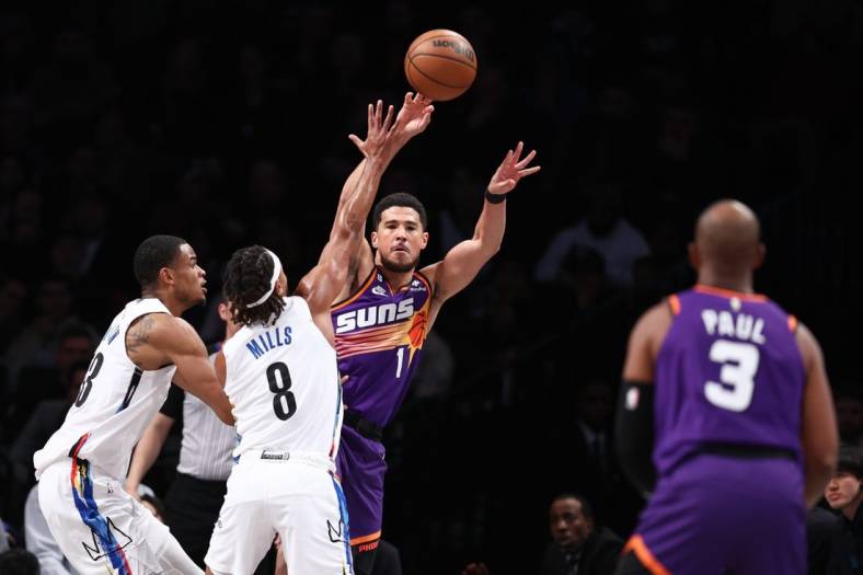Feb 7, 2023; Brooklyn, New York, USA; Phoenix Suns guard Devin Booker (1) passes the ball to guard Chris Paul (3) as Brooklyn Nets guard Patty Mills (8) and center Nic Claxton (33) defend during the first half at Barclays Center. Mandatory Credit: Vincent Carchietta-USA TODAY Sports