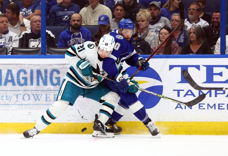Feb 7, 2023; Tampa, Florida, USA; San Jose Sharks center Michael Eyssimont (21)  and Tampa Bay Lightning left wing Nicholas Paul (20)  fight to control the puck during the second period at Amalie Arena. Mandatory Credit: Kim Klement-USA TODAY Sports