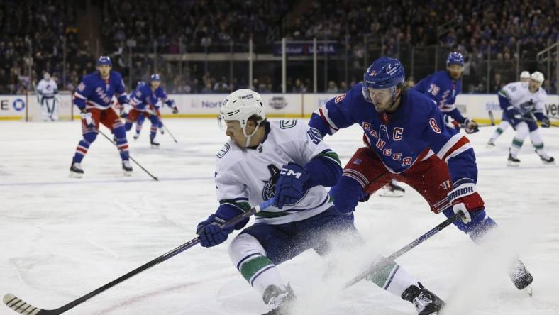 Feb 8, 2023; New York, New York, USA; New York Rangers left wing Artemi Panarin (10) skates with puck against Vancouver Canucks center J.T. Miller (9) at Madison Square Garden. Mandatory Credit: Jessica Alcheh-USA TODAY Sports