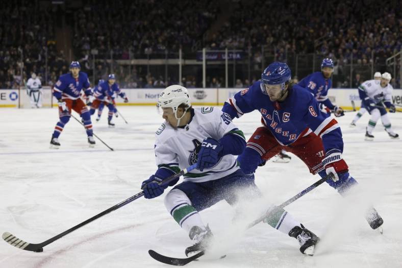 Feb 8, 2023; New York, New York, USA; New York Rangers left wing Artemi Panarin (10) skates with puck against Vancouver Canucks center J.T. Miller (9) at Madison Square Garden. Mandatory Credit: Jessica Alcheh-USA TODAY Sports