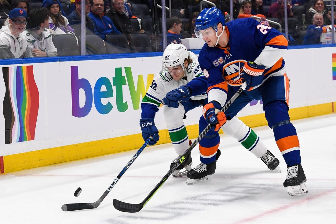 Feb 9, 2023; Elmont, New York, USA; New York Islanders defenseman Scott Mayfield (24) and Vancouver Canucks right wing Vasily Podkolzin (92) battle for a loose puck during the first period at UBS Arena. Mandatory Credit: Dennis Schneidler-USA TODAY Sports