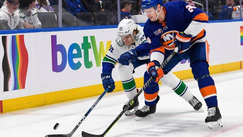 Feb 9, 2023; Elmont, New York, USA; New York Islanders defenseman Scott Mayfield (24) and Vancouver Canucks right wing Vasily Podkolzin (92) battle for a loose puck during the first period at UBS Arena. Mandatory Credit: Dennis Schneidler-USA TODAY Sports