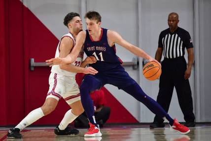 Feb 9, 2023; Los Angeles, California, USA; St. Mary's Gaels center Mitchell Saxen (11) moves the ball against Loyola Marymount Lions forward Alex Merkviladze (23) during the first half at Gersten Pavilion. Mandatory Credit: Gary A. Vasquez-USA TODAY Sports