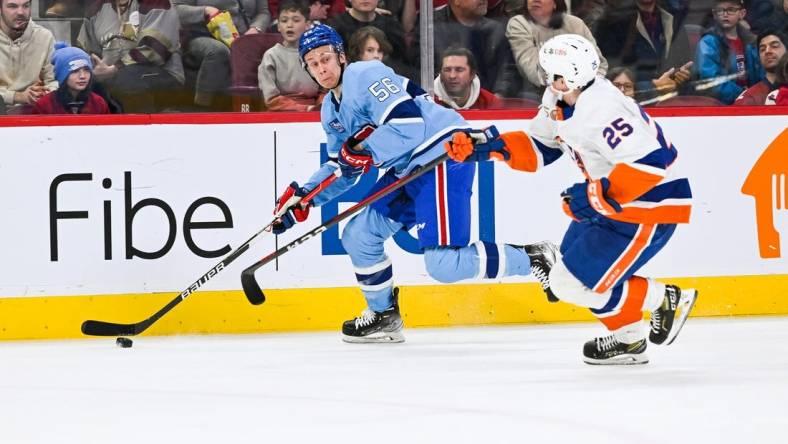 Feb 11, 2023; Montreal, Quebec, CAN; Montreal Canadiens right wing Jesse Ylonen (56) plays the puck against New York Islanders defenseman Sebastian Aho (25) during the second period at Bell Centre. Mandatory Credit: David Kirouac-USA TODAY Sports