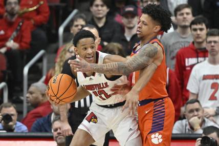Feb 18, 2023; Louisville, Kentucky, USA;  Louisville Cardinals forward JJ Traynor (12) posts up against Clemson Tigers guard Brevin Galloway (11) during the first half at KFC Yum! Center. Mandatory Credit: Jamie Rhodes-USA TODAY Sports