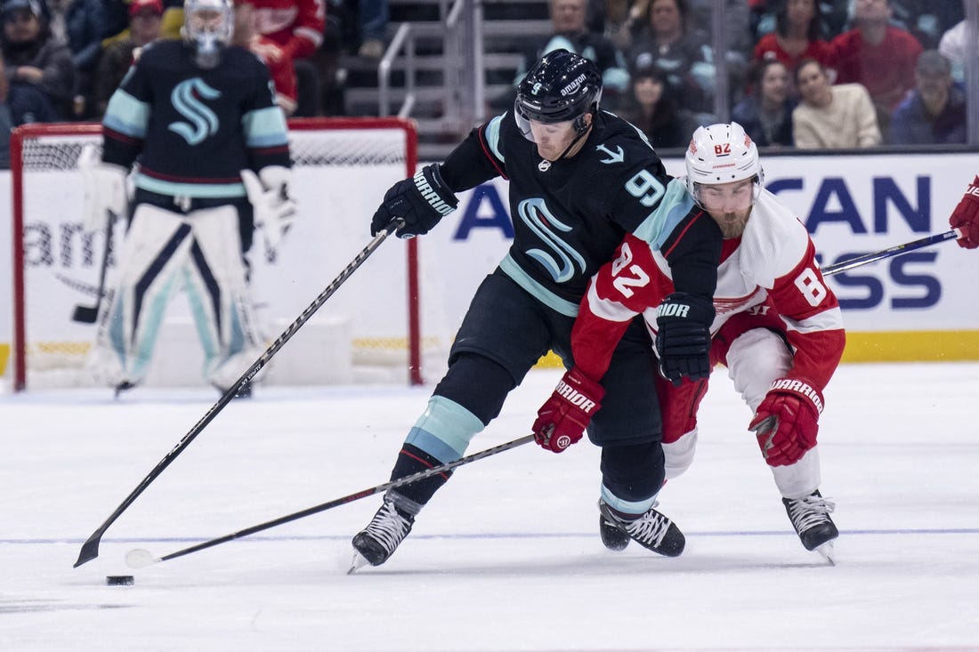 Feb 18, 2023; Seattle, Washington, USA; Seattle Kraken forward Ryan Donato (9) and Detroit Red Wings defenseman Jordan Oesterle (82) battle for the puck during the first period at Climate Pledge Arena. Mandatory Credit: Stephen Brashear-USA TODAY Sports