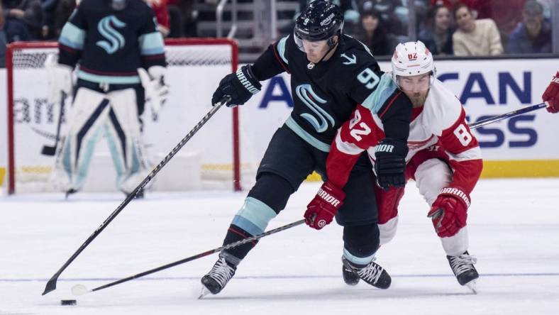 Feb 18, 2023; Seattle, Washington, USA; Seattle Kraken forward Ryan Donato (9) and Detroit Red Wings defenseman Jordan Oesterle (82) battle for the puck during the first period at Climate Pledge Arena. Mandatory Credit: Stephen Brashear-USA TODAY Sports