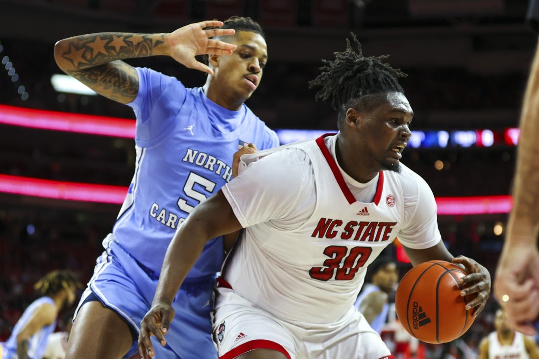 Feb 19, 2023; Raleigh, North Carolina, USA;  North Carolina State Wolfpack forward D.J. Burns Jr. (30) maintains possession against North Carolina Tar Heels forward Armando Bacot (5) during the first half of the game at PNC Arena. Mandatory Credit: Jaylynn Nash-USA TODAY Sports