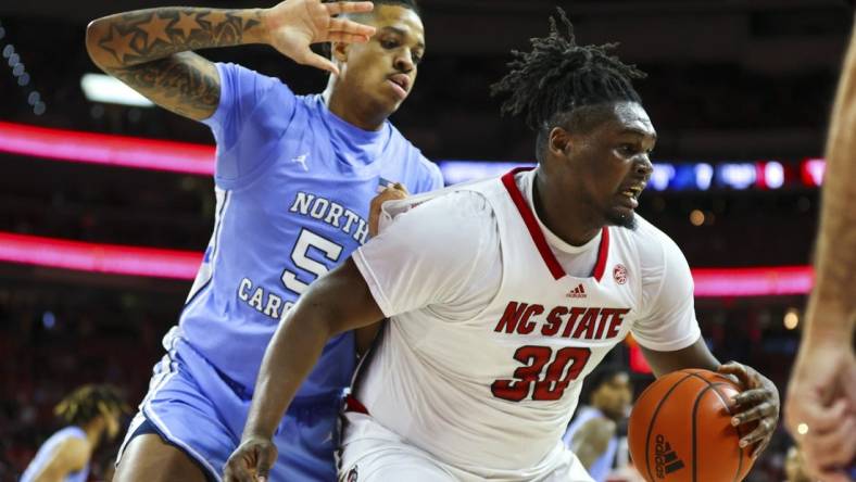 Feb 19, 2023; Raleigh, North Carolina, USA;  North Carolina State Wolfpack forward D.J. Burns Jr. (30) maintains possession against North Carolina Tar Heels forward Armando Bacot (5) during the first half of the game at PNC Arena. Mandatory Credit: Jaylynn Nash-USA TODAY Sports