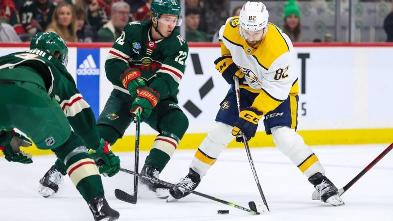 Feb 19, 2023; Saint Paul, Minnesota, USA; Nashville Predators center Tommy Novak (82) skates with the puck while Minnesota Wild left wing Matt Boldy (12) defends during the first period at Xcel Energy Center. Mandatory Credit: Matt Krohn-USA TODAY Sports