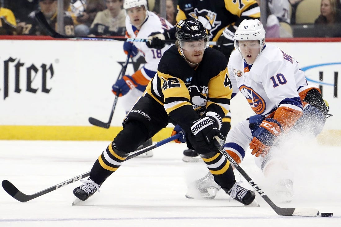 Feb 20, 2023; Pittsburgh, Pennsylvania, USA;  Pittsburgh Penguins right wing Kasperi Kapanen (42) moves the puck against New York Islanders right wing Simon Holmstrom (10) during the second period at PPG Paints Arena. The Islanders won 4-2. Mandatory Credit: Charles LeClaire-USA TODAY Sports