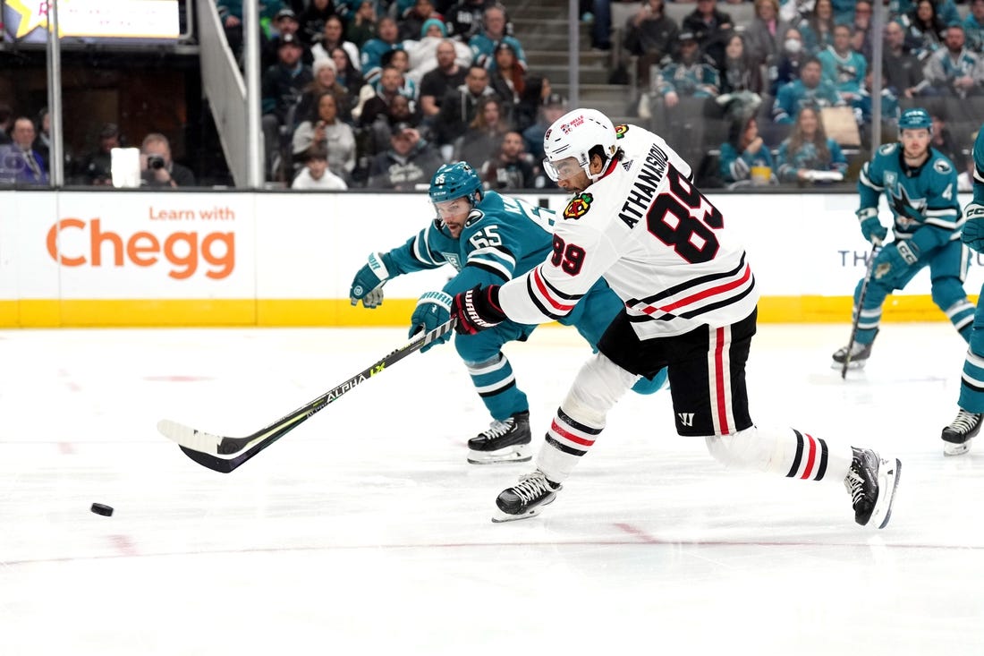 Feb 25, 2023; San Jose, California, USA; Chicago Blackhawks center Andreas Athanasiou (89) shoots against San Jose Sharks defenseman Erik Karlsson (65) during the first period at SAP Center at San Jose. Mandatory Credit: Darren Yamashita-USA TODAY Sports