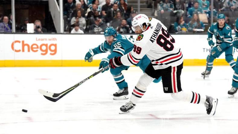 Feb 25, 2023; San Jose, California, USA; Chicago Blackhawks center Andreas Athanasiou (89) shoots against San Jose Sharks defenseman Erik Karlsson (65) during the first period at SAP Center at San Jose. Mandatory Credit: Darren Yamashita-USA TODAY Sports