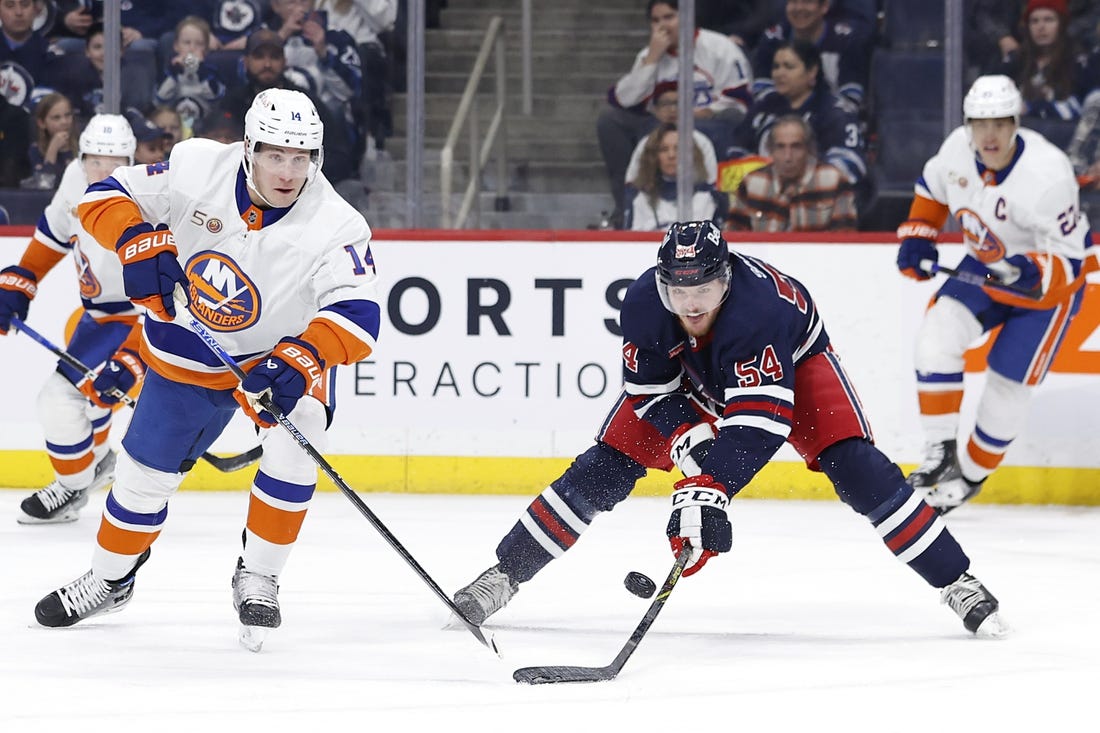 Feb 26, 2023; Winnipeg, Manitoba, CAN;New York Islanders center Bo Horvat (14) and Winnipeg Jets defenseman Dylan Samberg (54) chase for the puck in the first period at Canada Life Centre. Mandatory Credit: James Carey Lauder-USA TODAY Sports