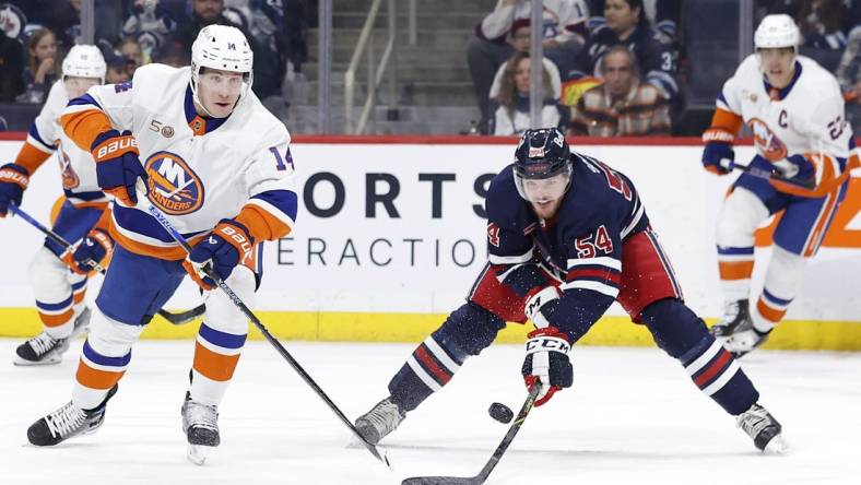 Feb 26, 2023; Winnipeg, Manitoba, CAN;New York Islanders center Bo Horvat (14) and Winnipeg Jets defenseman Dylan Samberg (54) chase for the puck in the first period at Canada Life Centre. Mandatory Credit: James Carey Lauder-USA TODAY Sports