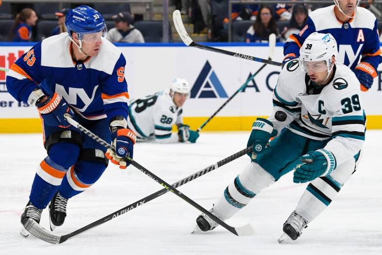 Oct 18, 2022; Elmont, New York, USA; San Jose Sharks center Logan Couture (39) and New York Islanders center Casey Cizikas (53) battle for a loose puck during the third period at UBS Arena. Mandatory Credit: Dennis Schneidler-USA TODAY Sports