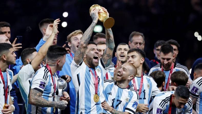 Dec 18, 2022; Lusail, Qatar; Argentina defender Nicolas Otamendi (19) holds up the World Cup trophy as he and his teammates celebrate after winning the 2022 World Cup final against France at Lusail Stadium. Mandatory Credit: Yukihito Taguchi-USA TODAY Sports