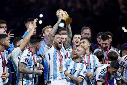 Dec 18, 2022; Lusail, Qatar; Argentina defender Nicolas Otamendi (19) holds up the World Cup trophy as he and his teammates celebrate after winning the 2022 World Cup final against France at Lusail Stadium. Mandatory Credit: Yukihito Taguchi-USA TODAY Sports