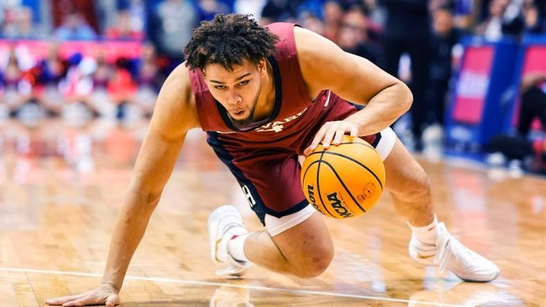 Dec 22, 2022; Lawrence, Kansas, USA; Harvard Crimson forward Chris Ledlum (4) slips while dribbling the ball during the first half against the Kansas Jayhawks at Allen Fieldhouse. Mandatory Credit: Jay Biggerstaff-USA TODAY Sports