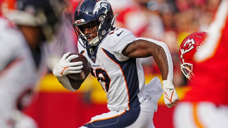 Jan 1, 2023; Kansas City, Missouri, USA; Denver Broncos running back Chase Edmonds (19) runs the ball against Kansas City Chiefs safety Justin Reid (20) during the first half at GEHA Field at Arrowhead Stadium. Mandatory Credit: Jay Biggerstaff-USA TODAY Sports