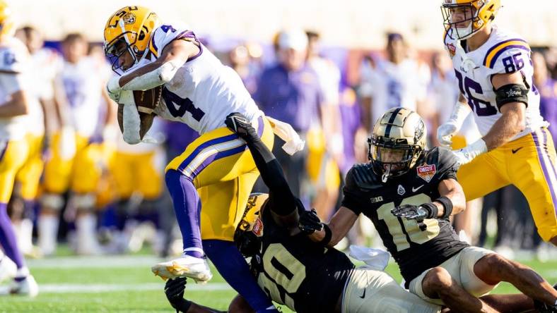 Jan 2, 2023; Orlando, FL, USA; Purdue Boilermakers linebacker OC Brothers (20) and Purdue Boilermakers safety Cam Allen (10) attempt to tackle LSU Tigers running back John Emery Jr. (4) during the second half at Camping World Stadium. Mandatory Credit: Matt Pendleton-USA TODAY Sports