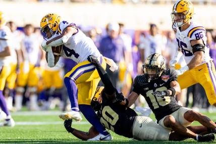 Jan 2, 2023; Orlando, FL, USA; Purdue Boilermakers linebacker OC Brothers (20) and Purdue Boilermakers safety Cam Allen (10) attempt to tackle LSU Tigers running back John Emery Jr. (4) during the second half at Camping World Stadium. Mandatory Credit: Matt Pendleton-USA TODAY Sports