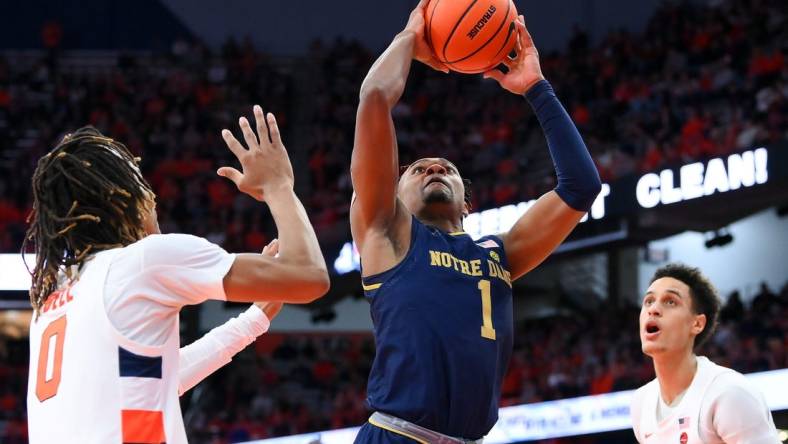 Jan 14, 2023; Syracuse, New York, USA; Notre Dame Fighting Irish guard J.J. Starling (1) drives to the basket between Syracuse Orange forward Chris Bell (0) and center Jesse Edwards (right) during the second half at the JMA Wireless Dome. Mandatory Credit: Rich Barnes-USA TODAY Sports