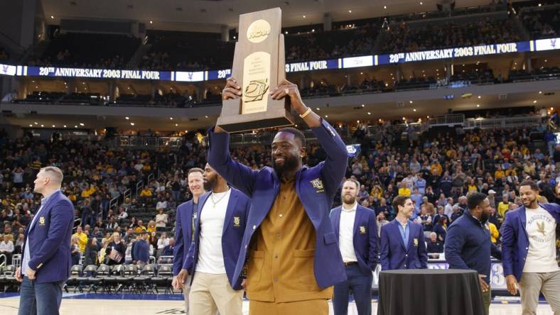 Jan 18, 2023; Milwaukee, Wisconsin, USA;  Former Marquette Golden Eagles player Dwayne Wade holds up the 2003 Division One Semifinalist trophy during a ceremony honoring the 20th anniversary of reaching the Final Four during halftime of the game between the Providence Friars and Marquette Golden Eagles at Fiserv Forum. Mandatory Credit: Jeff Hanisch-USA TODAY Sports