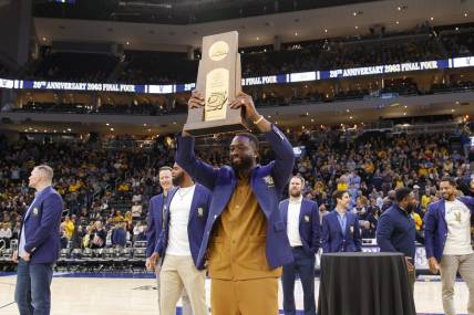 Jan 18, 2023; Milwaukee, Wisconsin, USA;  Former Marquette Golden Eagles player Dwayne Wade holds up the 2003 Division One Semifinalist trophy during a ceremony honoring the 20th anniversary of reaching the Final Four during halftime of the game between the Providence Friars and Marquette Golden Eagles at Fiserv Forum. Mandatory Credit: Jeff Hanisch-USA TODAY Sports