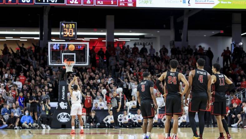 Feb 22, 2023; Cincinnati, Ohio, USA;  Members of the Temple Owls stand on the court as Cincinnati Bearcats guard David DeJulius (5) shoots a technical free throw in the second half at Fifth Third Arena. Mandatory Credit: Aaron Doster-USA TODAY Sports