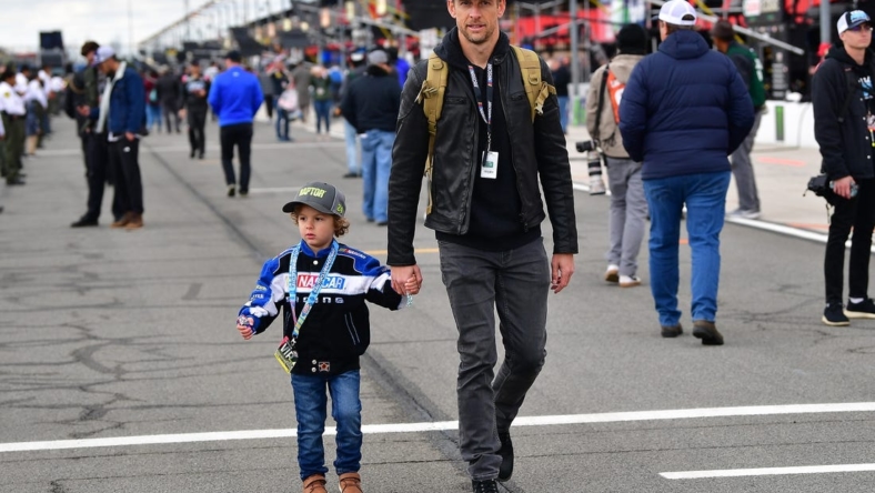 Feb 26, 2023; Fontana, California, USA; Former formula one driver Jenson Button with son Hendrix in attendance at the Pala Casino 400 at Auto Club Speedway. Mandatory Credit: Gary A. Vasquez-USA TODAY Sports