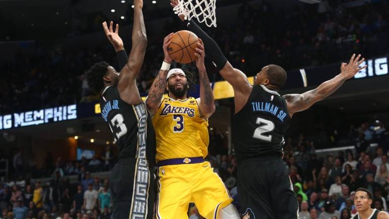 Feb 28, 2023; Memphis, Tennessee, USA; Los Angeles Lakers forward Anthony Davis (3) drives to the basket between Memphis Grizzlies forward Jaren Jackson Jr. (13) and forward Brandon Clark (15) during the second half at FedExForum. Mandatory Credit: Petre Thomas-USA TODAY Sports