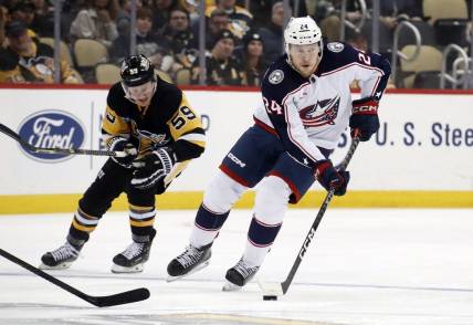 Mar 7, 2023; Pittsburgh, Pennsylvania, USA;  Columbus Blue Jackets right wing Mathieu Olivier (24) skates with the puck as Pittsburgh Penguins left wing Jake Guentzel (59) chases during the first period at PPG Paints Arena. Mandatory Credit: Charles LeClaire-USA TODAY Sports