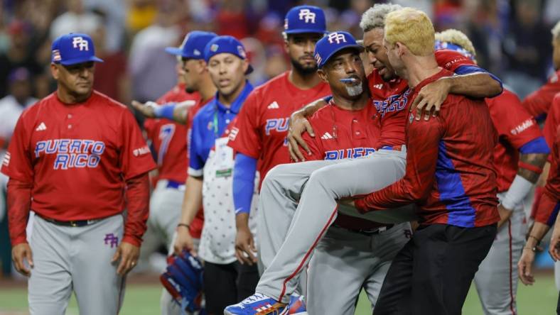 Mar 15, 2023; Miami, Florida, USA; Puerto Rico pitcher Edwin Diaz (39) gets taken off the field by pitching coach Ricky Bones (27) after an apparent leg injury during the team celebration against Dominican Republic at LoanDepot Park. Mandatory Credit: Sam Navarro-USA TODAY Sports