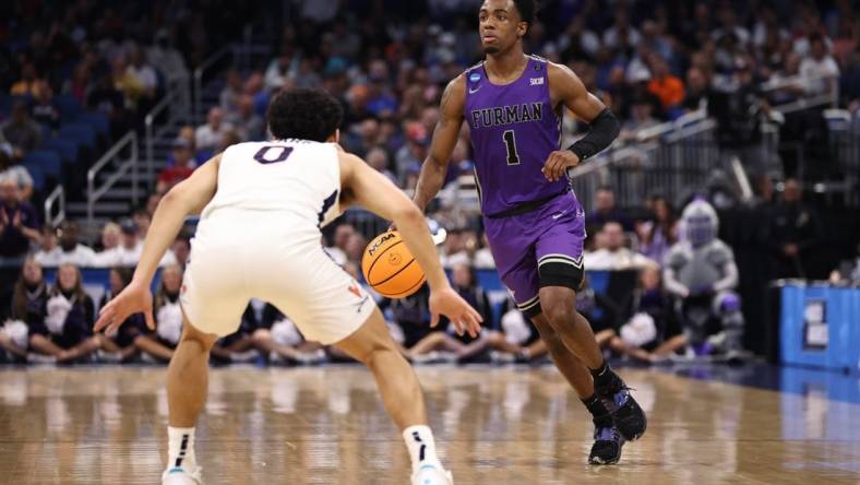 Mar 16, 2023; Orlando, FL, USA; Furman Paladins guard JP Pegues (1) dribbles the ball while defended by Virginia Cavaliers guard Kihei Clark (0) during the first half at Amway Center. Mandatory Credit: Matt Pendleton-USA TODAY Sports