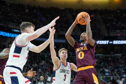 Mar 17, 2023; Albany, NY, USA; Iona Gaels guard Berrick JeanLouis (0) drives to the basket against UConn Huskies center Donovan Clingan (32) and guard Joey Calcaterra (3) during the first half at MVP Arena. Mandatory Credit: David Butler II-USA TODAY Sports