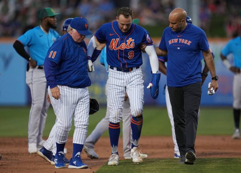 Mar 17, 2023; Port St. Lucie, Florida, USA;  New York Mets center fielder Brandon Nimmo (9) walks back to the dugout with the assistance of manager Buck Showalter (11) and a trainer in the fifth inning against the Miami Marlins at Clover Park. Mandatory Credit: Jim Rassol-USA TODAY Sports
