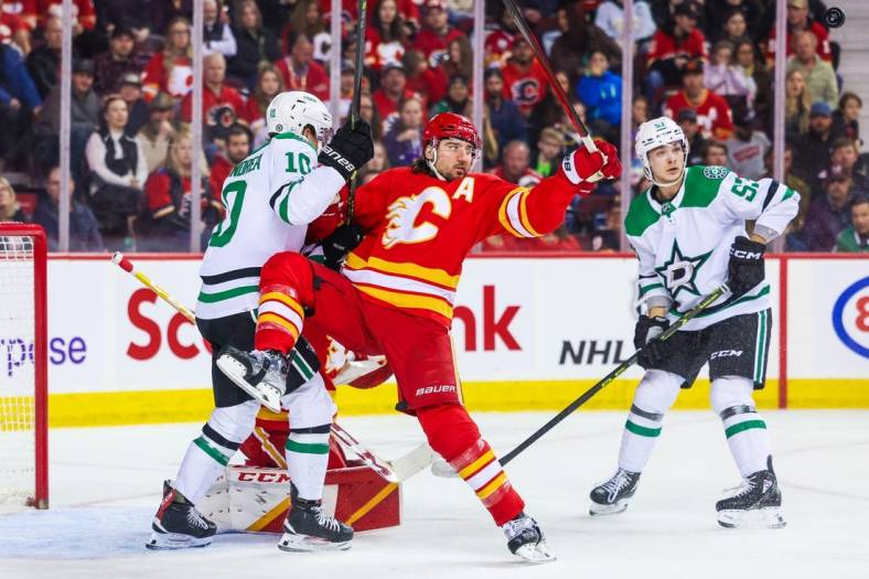 Mar 18, 2023; Calgary, Alberta, CAN; Calgary Flames defenseman Chris Tanev (8) and Dallas Stars center Ty Dellandrea (10) battle for the puck in front of Calgary Flames goaltender Jacob Markstrom (25) during the first period at Scotiabank Saddledome. Mandatory Credit: Sergei Belski-USA TODAY Sports