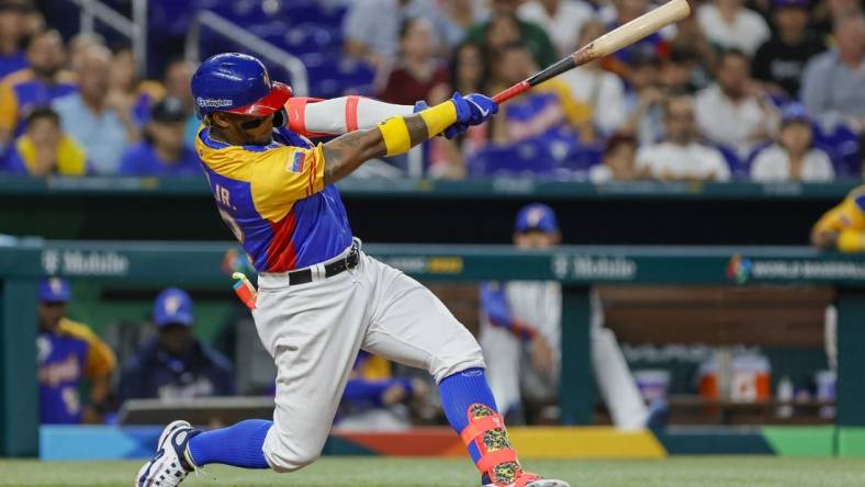 Mar 18, 2023; Miami, Florida, USA; Venezuela center fielder Ronald Acuna Jr. (42) hits a double during the eighth inning against the USA at LoanDepot Park. Mandatory Credit: Sam Navarro-USA TODAY Sports