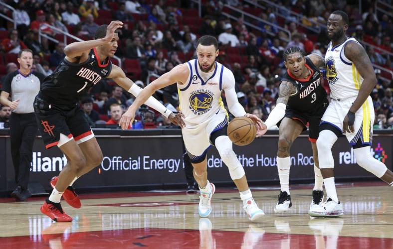 Mar 20, 2023; Houston, Texas, USA; Golden State Warriors guard Stephen Curry (30) drives with the ball as Houston Rockets forward Jabari Smith Jr. (1) and guard Kevin Porter Jr. (3) defend during the second quarter at Toyota Center. Mandatory Credit: Troy Taormina-USA TODAY Sports