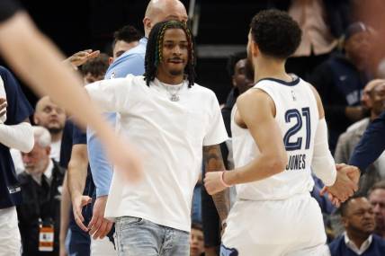 Mar 20, 2023; Memphis, Tennessee, USA; Memphis Grizzlies guard Ja Morant (left) reacts with guard Tyus Jones (21) during a timeout during the second half against the Dallas Mavericks at FedExForum. Mandatory Credit: Petre Thomas-USA TODAY Sports