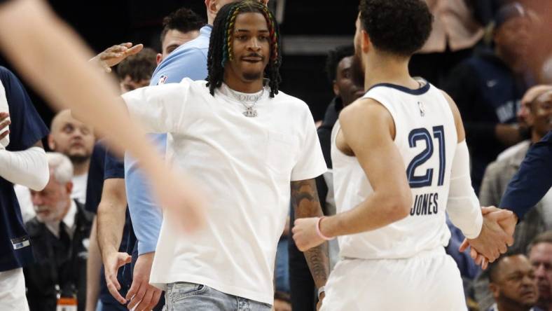 Mar 20, 2023; Memphis, Tennessee, USA; Memphis Grizzlies guard Ja Morant (left) reacts with guard Tyus Jones (21) during a timeout during the second half against the Dallas Mavericks at FedExForum. Mandatory Credit: Petre Thomas-USA TODAY Sports