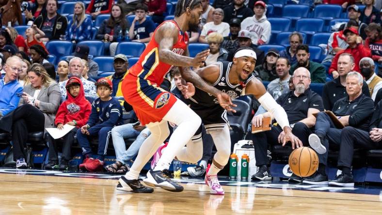 Mar 21, 2023; New Orleans, Louisiana, USA;  San Antonio Spurs guard Devonte' Graham (4) dribbles against New Orleans Pelicans forward Naji Marshall (8) during the first half at Smoothie King Center. Mandatory Credit: Stephen Lew-USA TODAY Sports