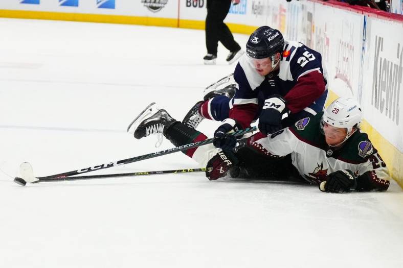 Mar 24, 2023; Denver, Colorado, USA; Arizona Coyotes center Barrett Hayton (29) and Colorado Avalanche right wing Logan O'Connor (25) reach for a loose puck in the third period at Ball Arena. Mandatory Credit: Ron Chenoy-USA TODAY Sports