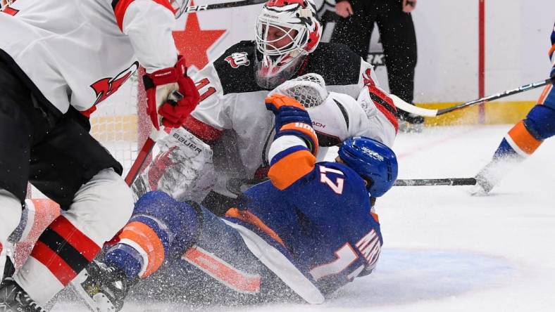 Mar 27, 2023; Elmont, New York, USA;  New York Islanders left wing Matt Martin (17) falls into New Jersey Devils goaltender Vitek Vanecek (41) during the second period at UBS Arena. Mandatory Credit: Dennis Schneidler-USA TODAY Sports