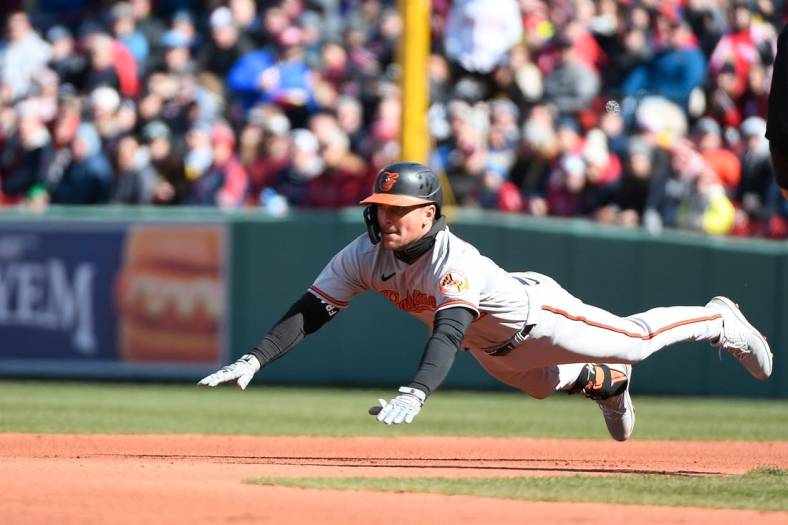 Mar 30, 2023; Boston, Massachusetts, USA; Baltimore Orioles second baseman Adam Frazier (12) dives for second base against the Boston Red Sox  at Fenway Park. Mandatory Credit: Eric Canha-USA TODAY Sports