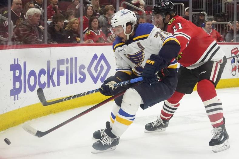 Mar 30, 2023; Chicago, Illinois, USA; St. Louis Blues defenseman Justin Faulk (72) and Chicago Blackhawks right wing Taylor Raddysh (11) go for the puck during the first period at United Center. Mandatory Credit: David Banks-USA TODAY Sports
